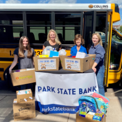 Park State Bank employees standing outside of a school bus with donations for the "Stuff The Bus" fund raiser for school supplies.